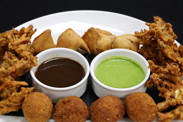 assorted indian snack pakora plater with paneer balls, onion crisps and panjabi samosa