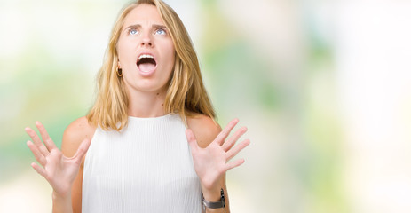 Beautiful young elegant woman over isolated background crazy and mad shouting and yelling with aggressive expression and arms raised. Frustration concept.