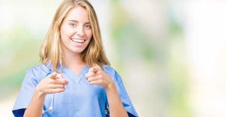 Beautiful young doctor woman wearing medical uniform over isolated background pointing fingers to camera with happy and funny face. Good energy and vibes.