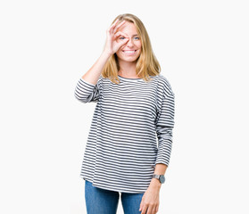 Fototapeta premium Beautiful young woman wearing stripes sweater over isolated background doing ok gesture with hand smiling, eye looking through fingers with happy face.