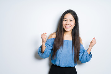 Beautiful brunette woman over isolated background celebrating surprised and amazed for success with arms raised and open eyes. Winner concept.