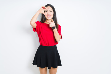 Beautiful brunette woman wearing red t-shirt and skirt over isolated background smiling making frame with hands and fingers with happy face. Creativity and photography concept.