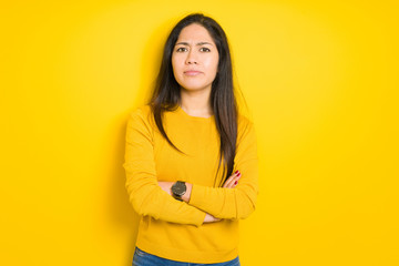 Beautiful brunette woman over yellow isolated background skeptic and nervous, disapproving expression on face with crossed arms. Negative person.