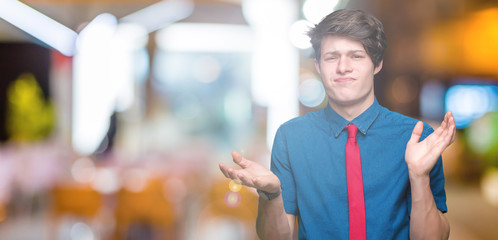 Young handsome business man wearing red tie over isolated background clueless and confused expression with arms and hands raised. Doubt concept.