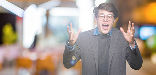 Young handsome business man wearing glasses over isolated background celebrating crazy and amazed...