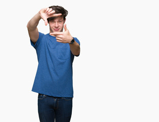 Naklejka premium Young handsome man wearing blue t-shirt over isolated background smiling making frame with hands and fingers with happy face. Creativity and photography concept.
