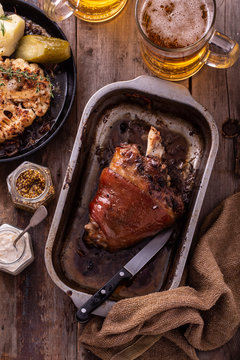 Baked Pork knuckle with beer and cauliflower in roast pan.