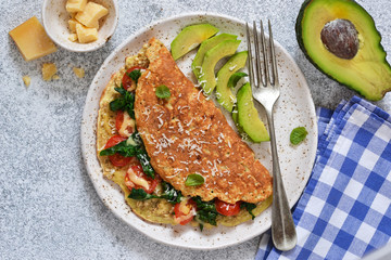 Omelet with tomatoes, cheese and basil in a plate on the kitchen table. View from above.