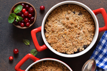 Crumble with cranberries and other berries, nuts on the kitchen table. View from above.