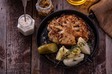 Vegetarian roasted cauliflower steak with potatoes on a frying pan