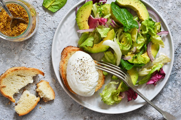 Fresh salad with spinach, avocado, egg plow and sauce on a concrete background. View from above.