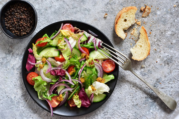 Vitamin salad of vegetables; spinach; cucumber; tomatoes and sauce on a concrete table. View from above.