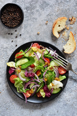 Vitamin salad of vegetables; spinach; cucumber; tomatoes and sauce on a concrete table. View from above.