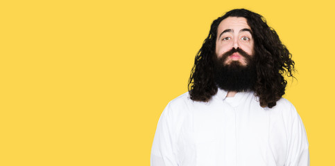 Man wearing Jesus Christ costume puffing cheeks with funny face. Mouth inflated with air, crazy expression.