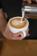 barista man preparing coffee (cappuccino), pouring milk
