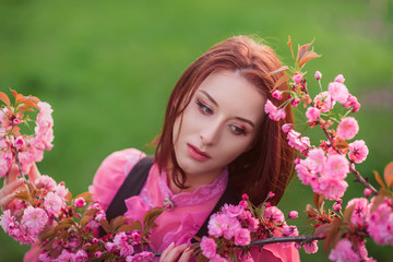 Fototapeta premium Beautiful woman in the garden of sakura. Retro clothes, pink blouse.