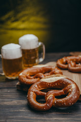 tasty pretzels on dark wooden background with draft beer in the mug in blurred background