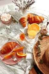 Croissants and oranges on a blue tablecloth
