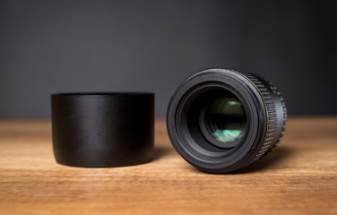 Digital camera lens with lens hood on a wooden table