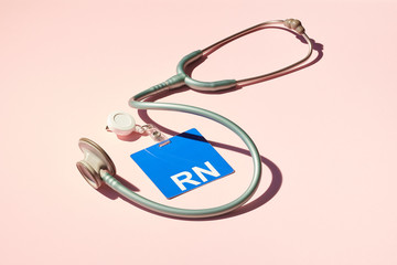 Registered Nurse ID Badge and Stethoscope on Pink Background 