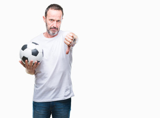 Middle age hoary senior man holding soccer football ball over isolated background with angry face, negative sign showing dislike with thumbs down, rejection concept