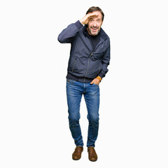 Fototapeta premium Middle age handsome man wearing a jacket very happy and smiling looking far away with hand over head. Searching concept.