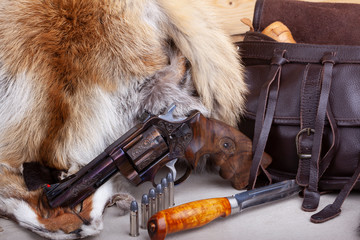 revolver handgun with knife and ammunition photographed on the fox skin