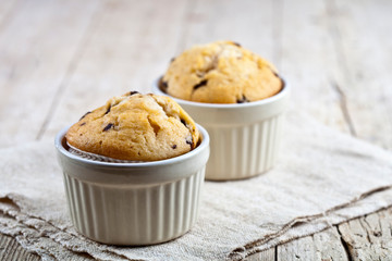 Homemade fresh muffins on ceramic white bowls on linen napkin.