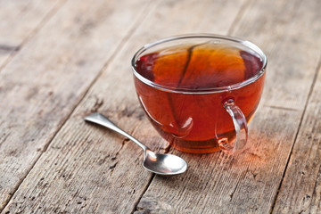 Cup of fresh tea and vintage spoon on rustic wooden table background.
