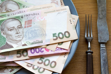 Closeup of Ukrainian money lying on a plate with a fork and knife