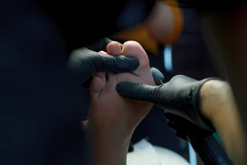 Fototapeten Foot skin treatment process. Gloved hands with a pedicure machine. Close-up © Sahaidachnyi Roman