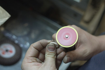 The master jeweler holds the working tool in his hands and makes jewelery at his workplace