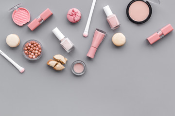 decorative cosmetics for make-up with macaroon cookies on gray tabletop background space for text