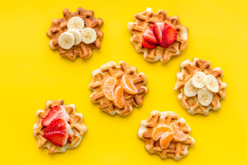 Obraz na płótnie Canvas homemade Belgian waffles with fruit topings on yellow background top view