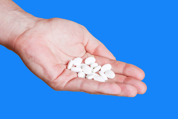 White pills on hand isolated on blue background.
