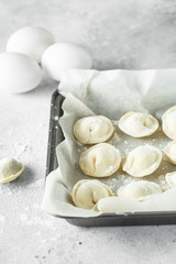 raw dumplings with meat on a baking tray