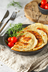 hot homemade pasties on a black dish served with tomatoes