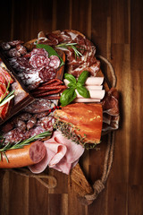 cold meat assortment with delicious salami and  fresh herbs . Variety of meat products including coppa and sausages