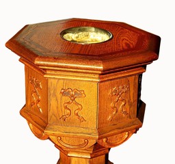 Close-up of antique wood eight sided baptismal font isolated on white with sun shining on it