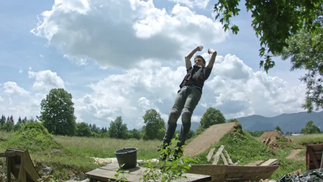 An athletic boy doing a backflip into fomepit in nature