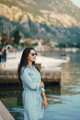 A beautiful young girl in a blue dress standing near water