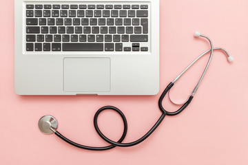 Stethoscope keyboard laptop computer isolated on pink background. Modern medical Information technology and sofware advances concept. Computer and gadget diagnostics and repair. Flat lay top view
