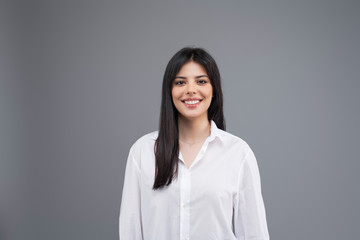 Portrait of a smiling young business woman in white shirt isolated over grey background