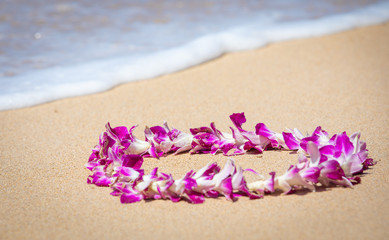 Fototapeta na wymiar Orchid Lei on a Maui beach with soft surf