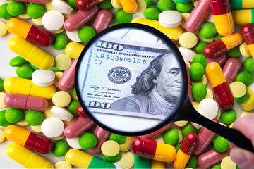 Many expensive tablets or capsules under a magnifying glass turn into money, symbolizing paid expensive drugs and corruption. Medicine, health and payment concept.