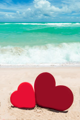 Two hearts on the sandy beach background