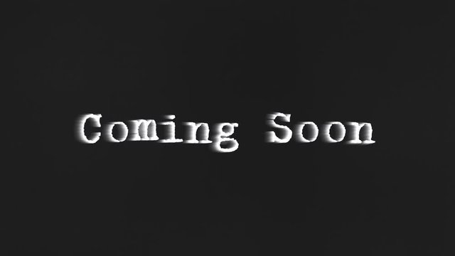 A scary text, Coming Soon, appearing on the screen with a light behind the typewriter font, typical of a horror flick (b-movie).