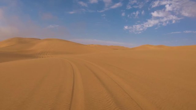 POV shot from the front of a safari vehicle moving through deep sand and dunes in the Namib Desert of Namibia.