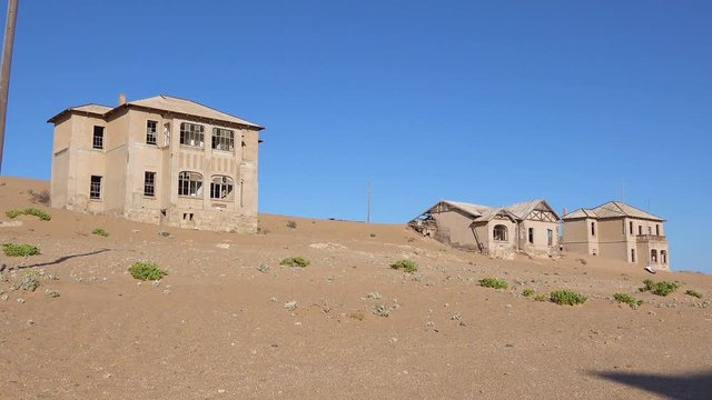 Exterior establishing shot of abandoned buildings in the Namib desert at the ghost town of Kolmanskop, Namibia.