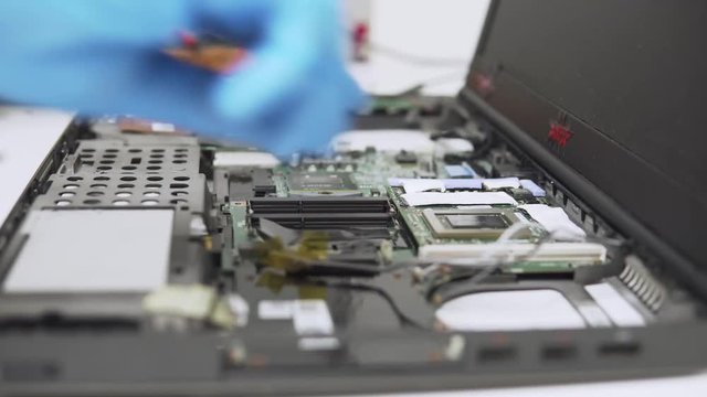 Time-lapse of mounting new parts in a laptop by a professinal technician with thermal paste and protective gloves.